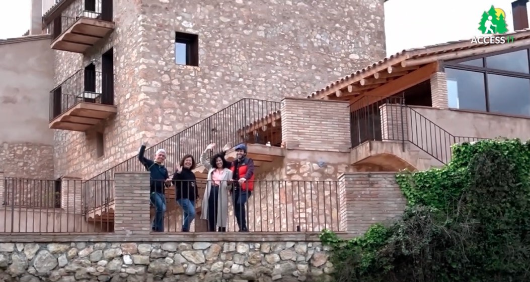 View of stone-built rural holiday accommodation with 4 people waving to camera