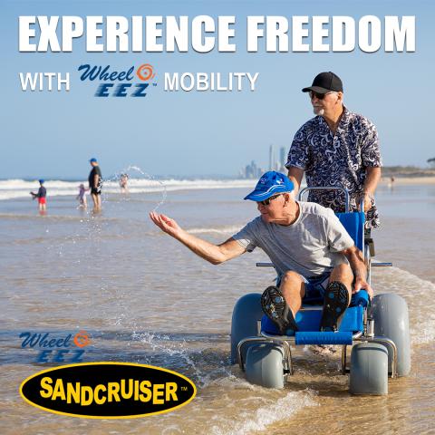 Wheeleez beach wheelchair on beach with older man seated and another pushingand 