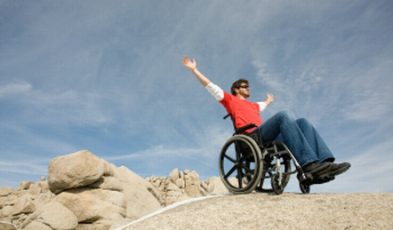 Male wheelchair user on rock with widespread arms