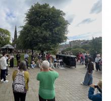 A Chinese youth orchestra gives a spontaneous concert of traditional music in a city park in Edinburgh, with tourist watching and filming the show.