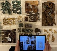 image of museum artefacts in open displays with hand-held tablet in foreground 